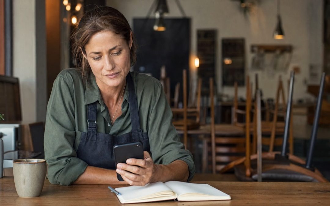 Restaurantbesitzerin liest Google-Bewertungen auf dem Smartphone und notiert eine professionelle Antwort.