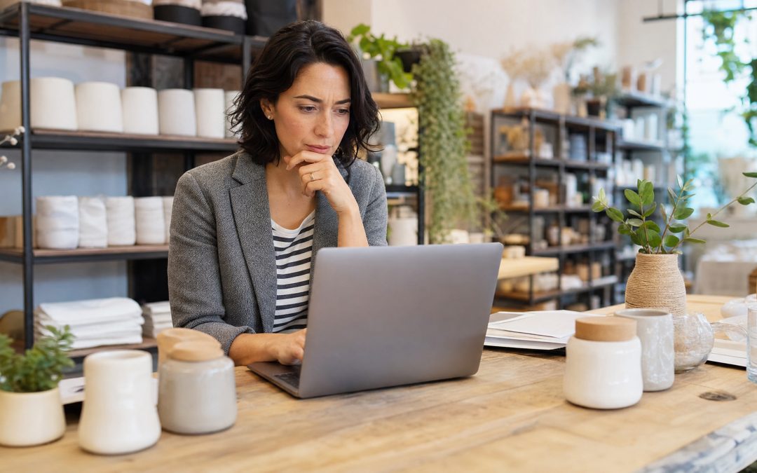 Händler vergleicht überlegt zwei Shopsysteme am Laptop